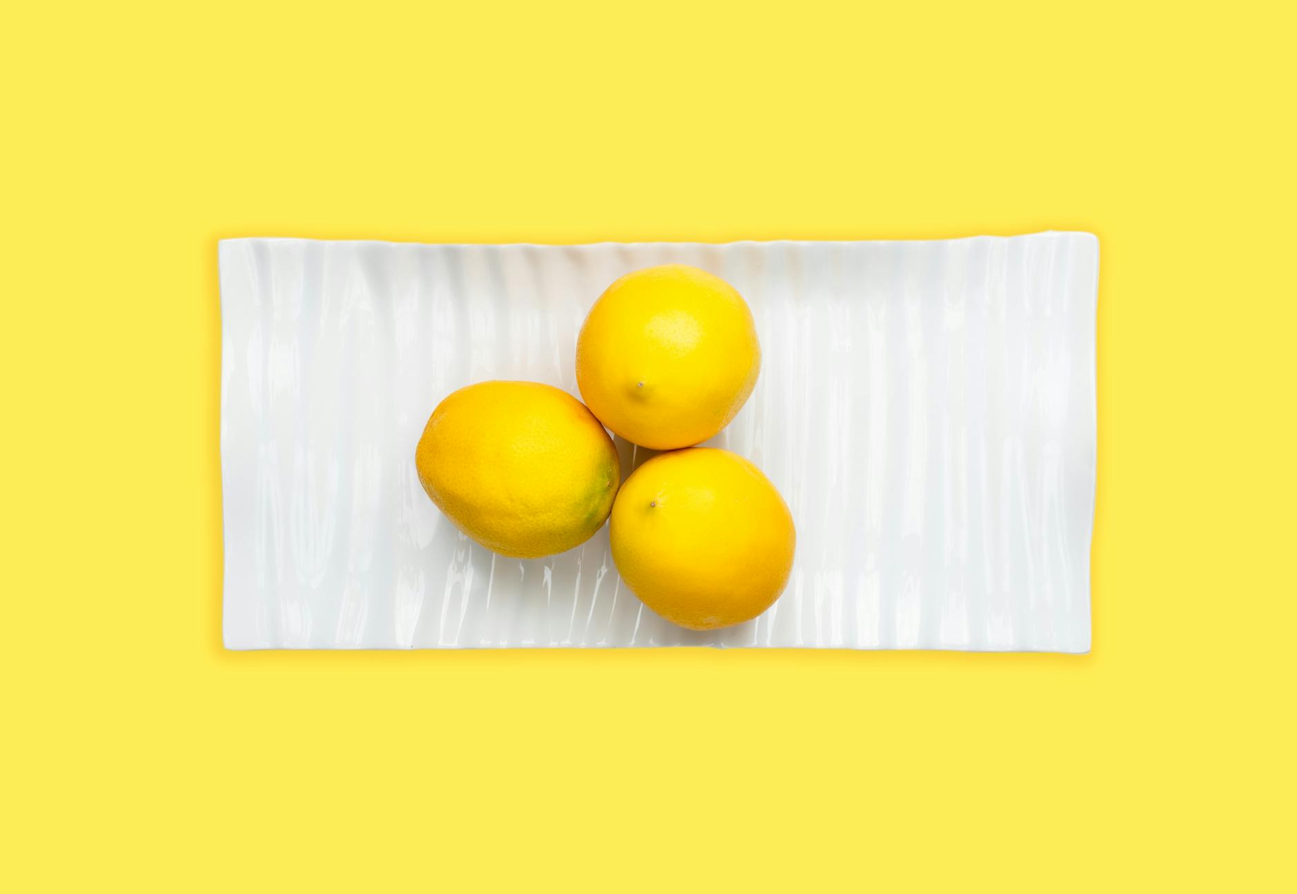 A hand holding a fresh lemon on a soft pink background, symbolizing the gentle yet powerful sensation of lemon vibrator technology.