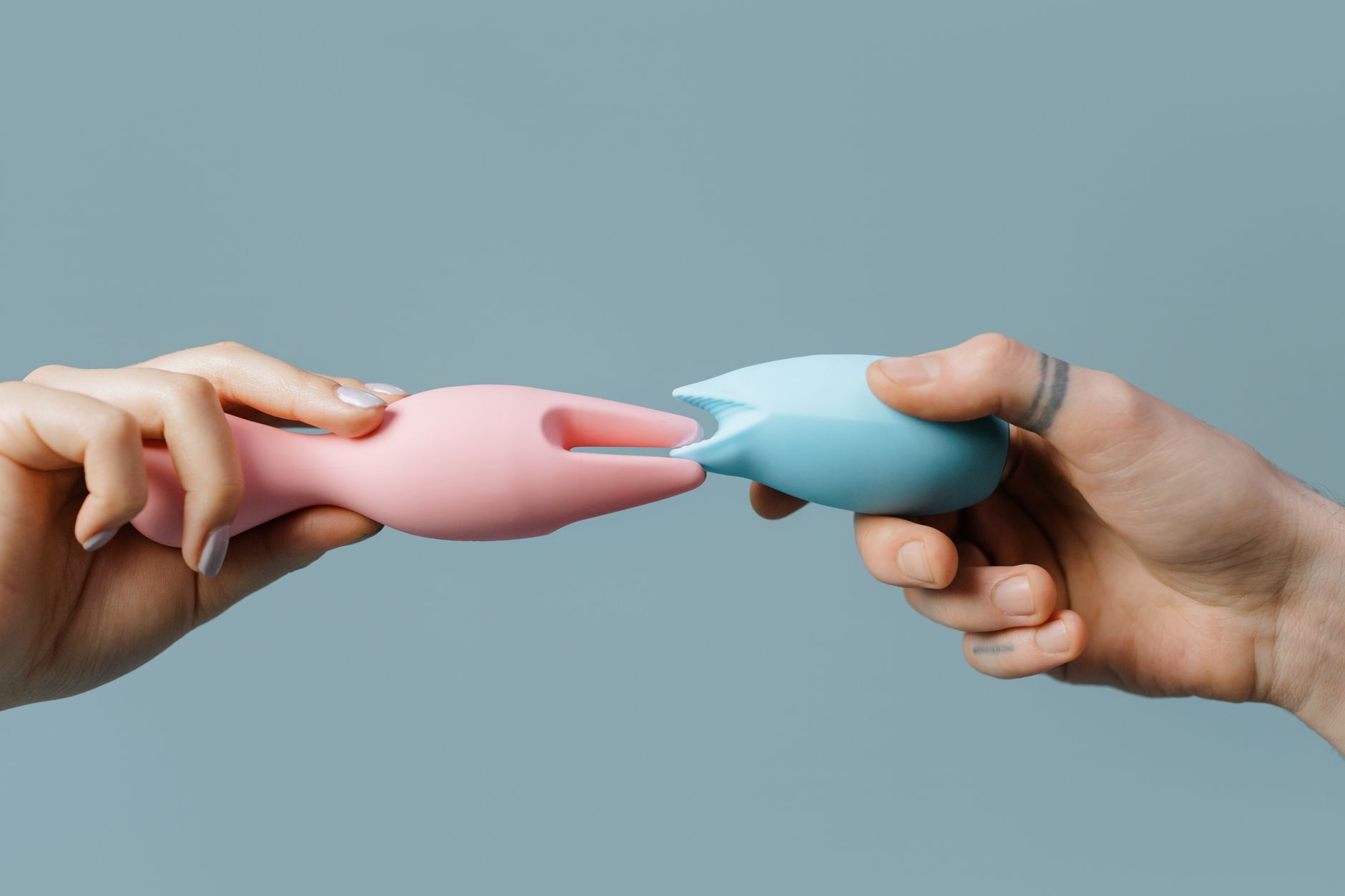 Hands holding colorful silicone sex toys, representing postpartum body reconnection and pleasure rebuilding