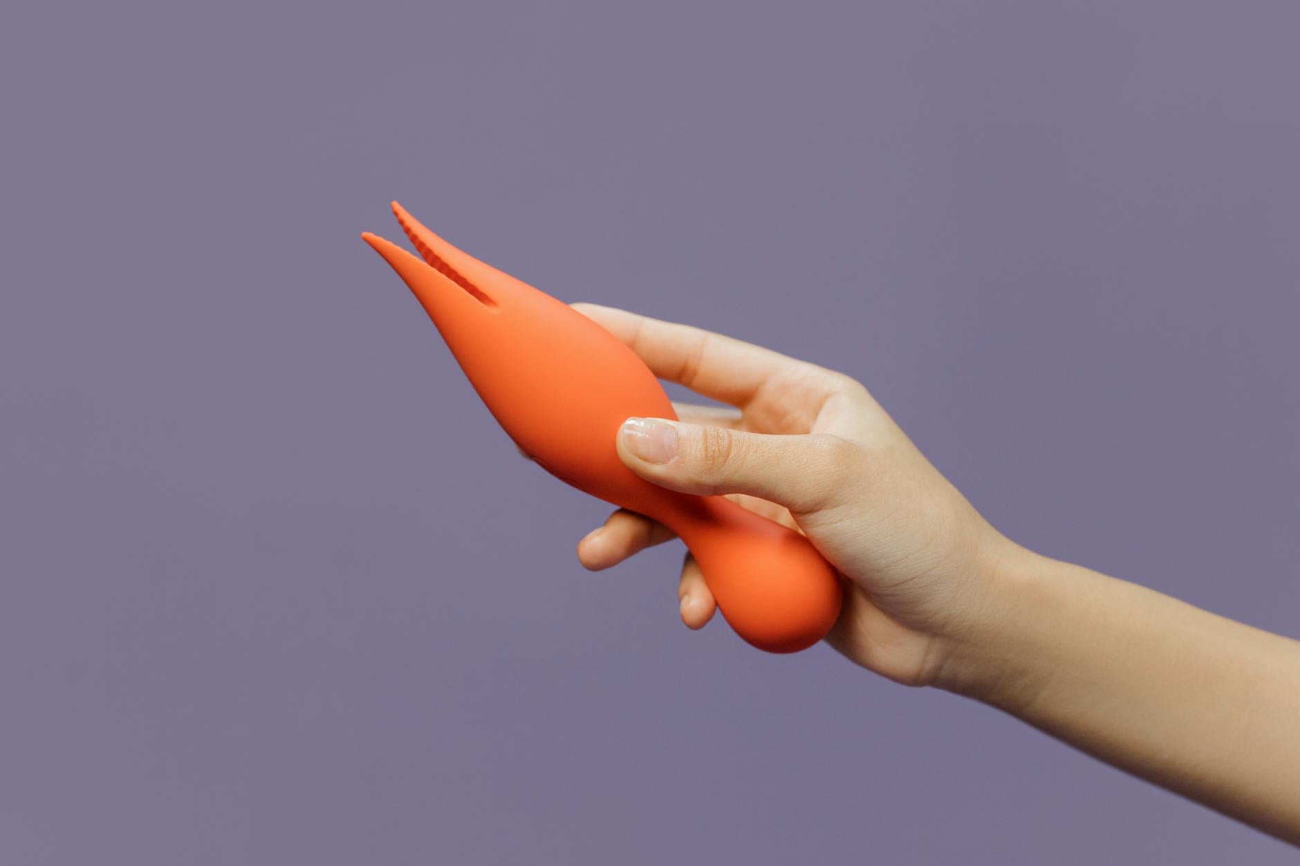 Close-up of hands holding a sleek vibrator against a minimalistic backdrop, representing intimate conversation and pleasure exploration