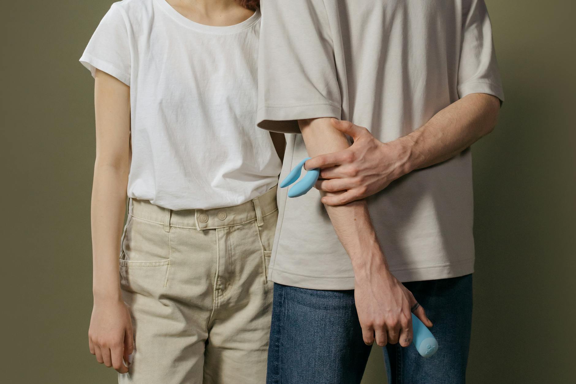 A couple exploring intimacy together with a blue vibrator in a light-filled bedroom